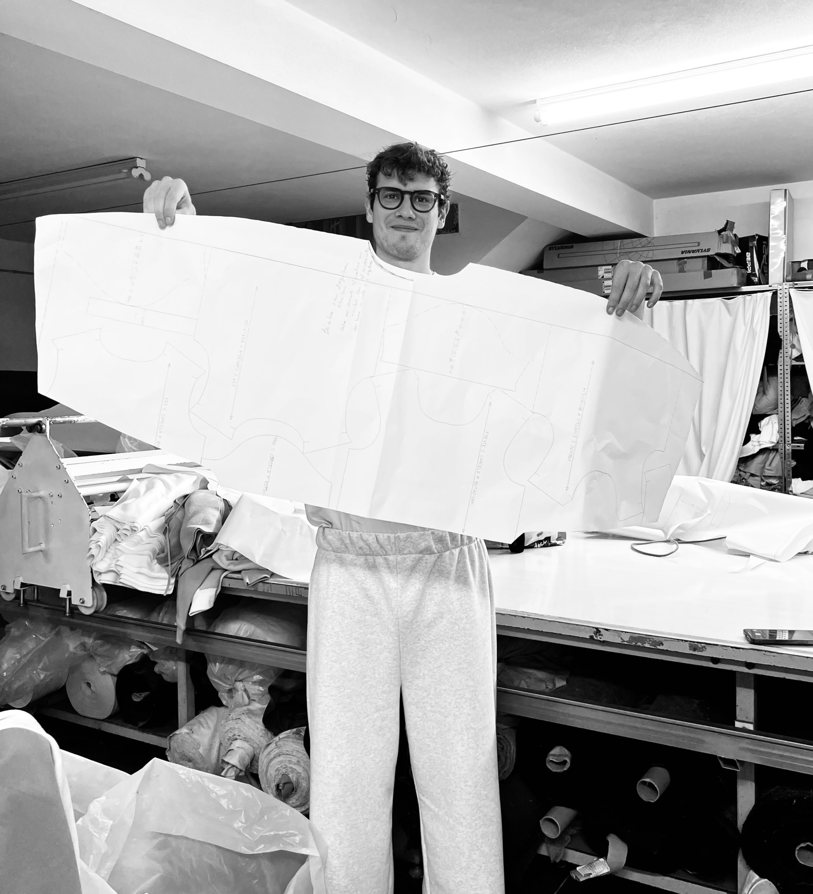 Person holding a large white object in an indoor setting with equipment and materials around