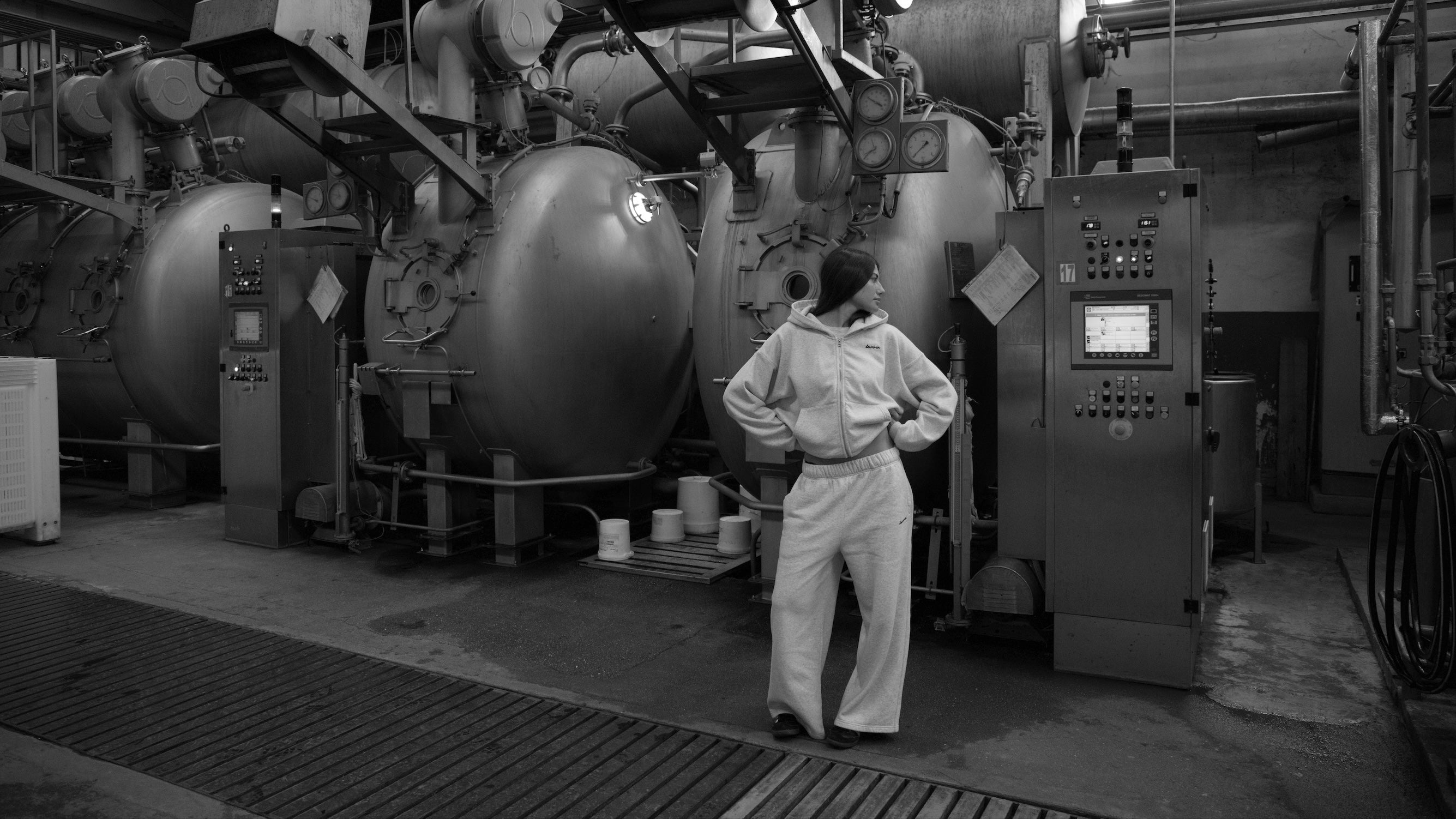 Person in a white jumpsuit standing in front of large industrial equipment in a factory setting