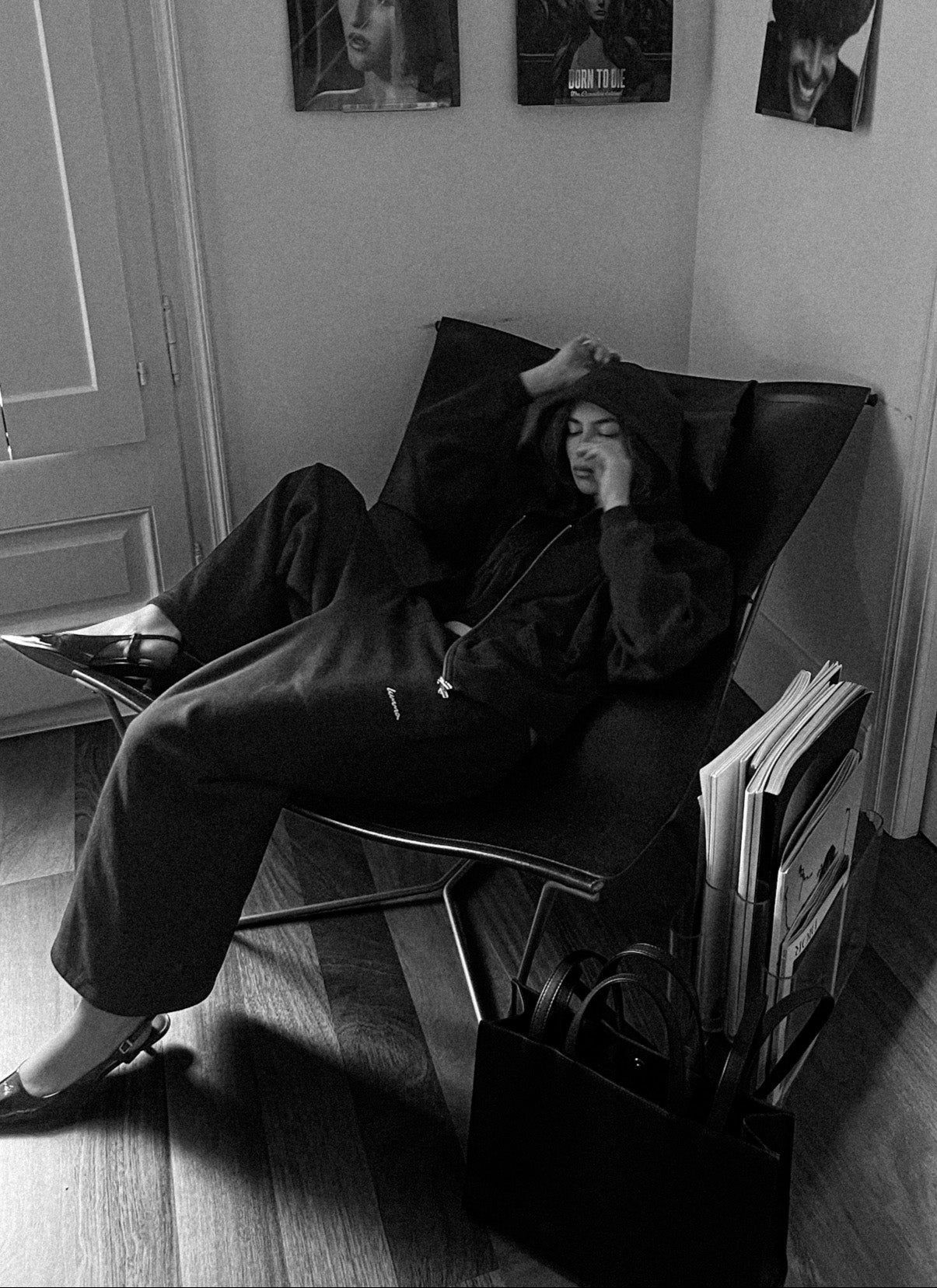 Person sitting in a chair with records around, in a room with album covers on the wall.