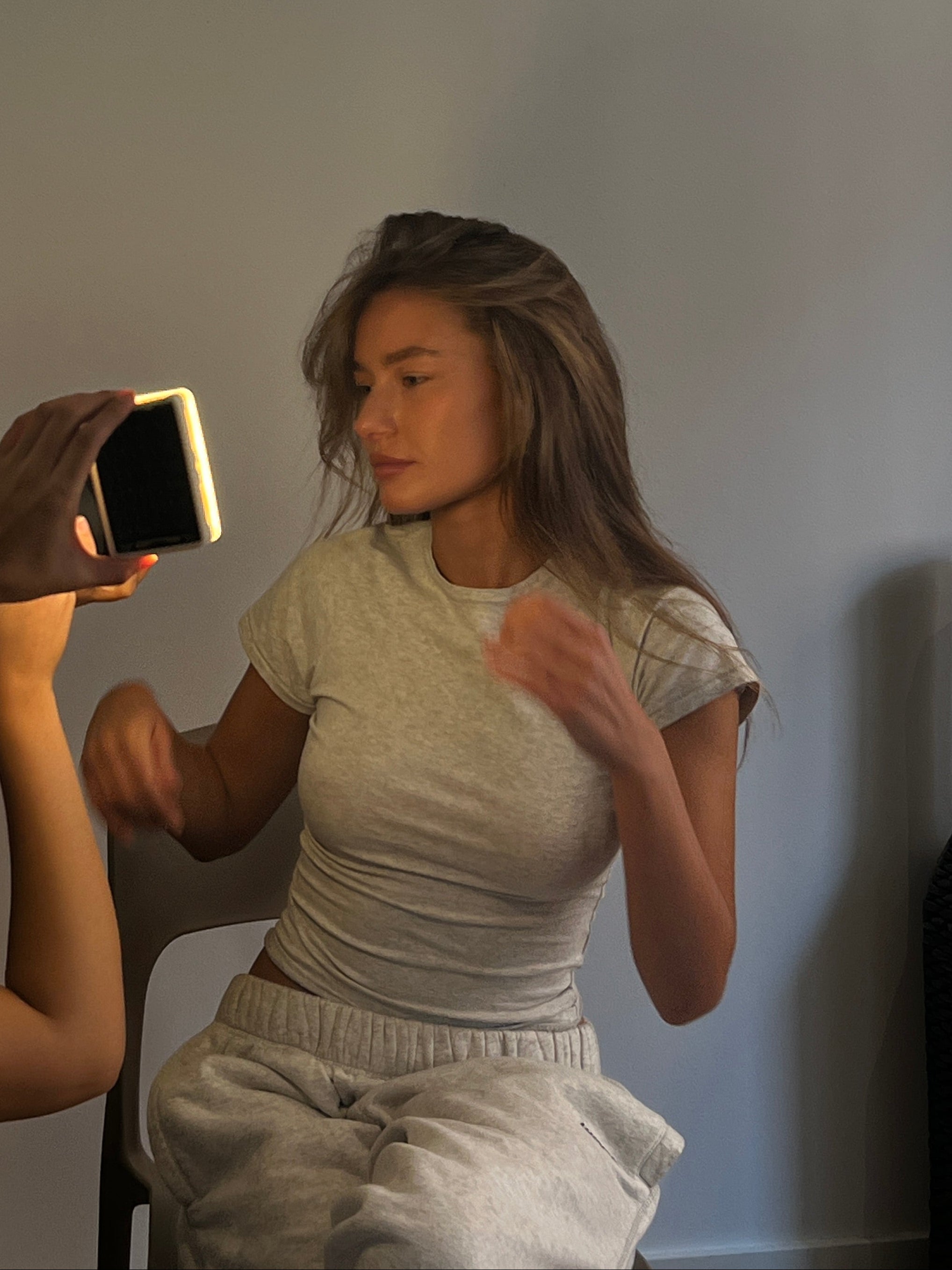 Two people interacting with a smartphone on a plain background